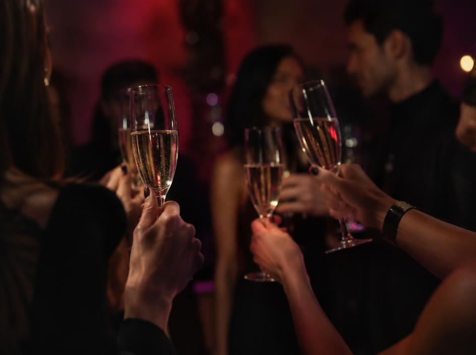 Guests raising champagne glasses at a dimly lit private party